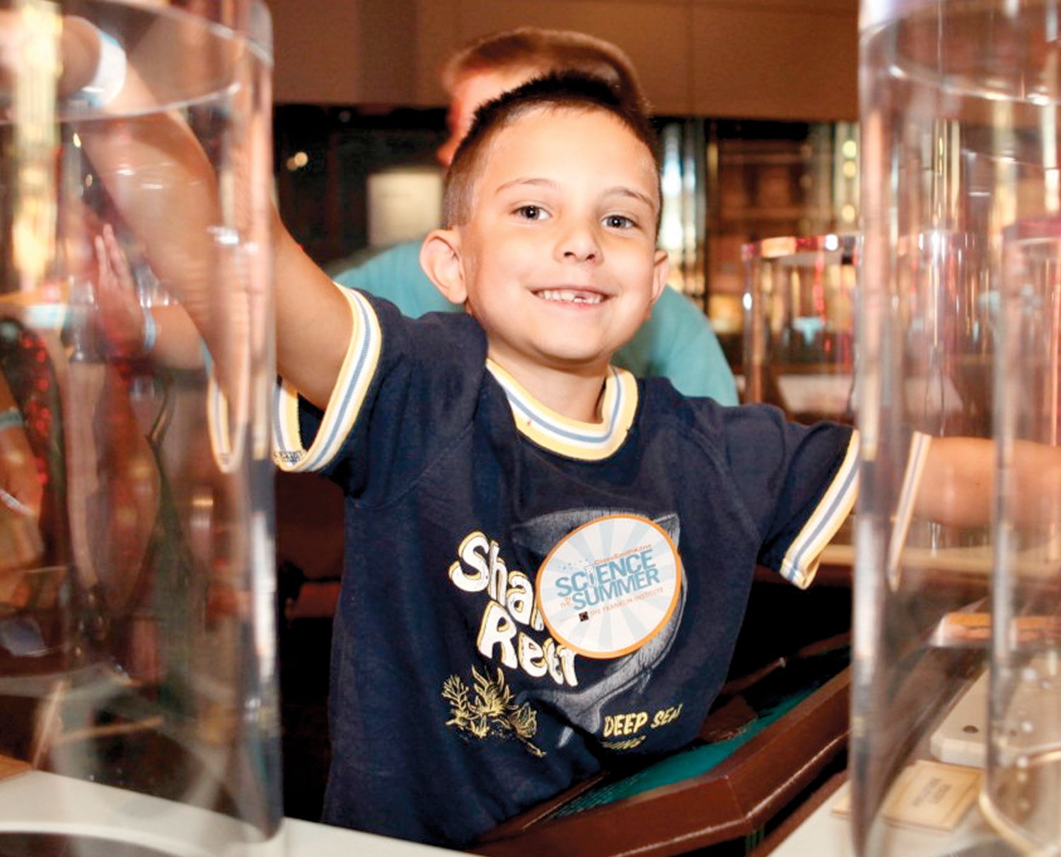 A young boy is smiling at the camera while enjoying the permanent exhibit, Electricity, at The Franklin Insitute.