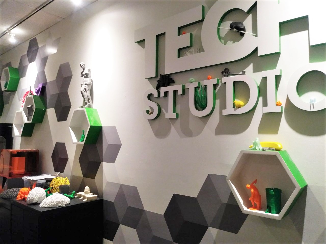 A wall at The Franklin Institute is decorated with hexagons and 3D printed objects and bears the label, "Tech Studio."