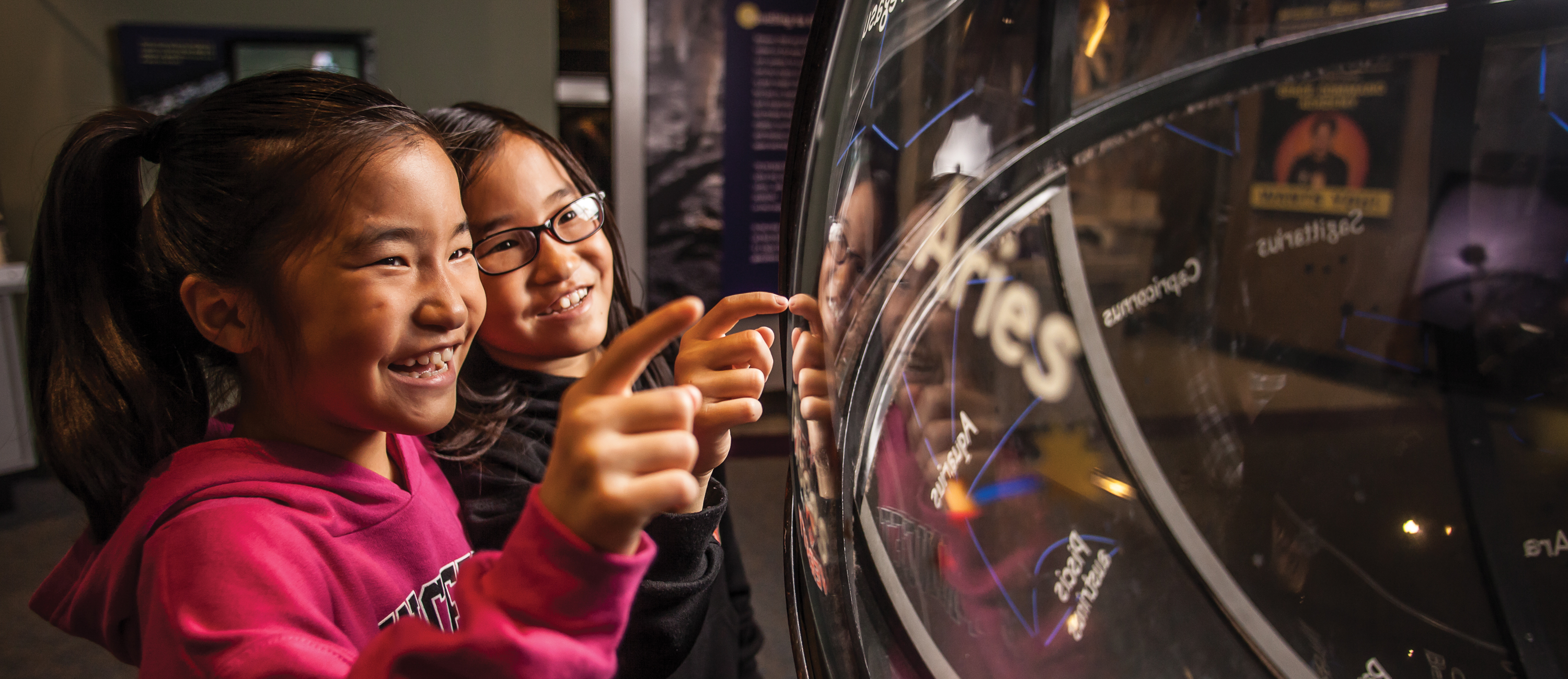 Two younger girls looking at the constellation globe in Space Command.