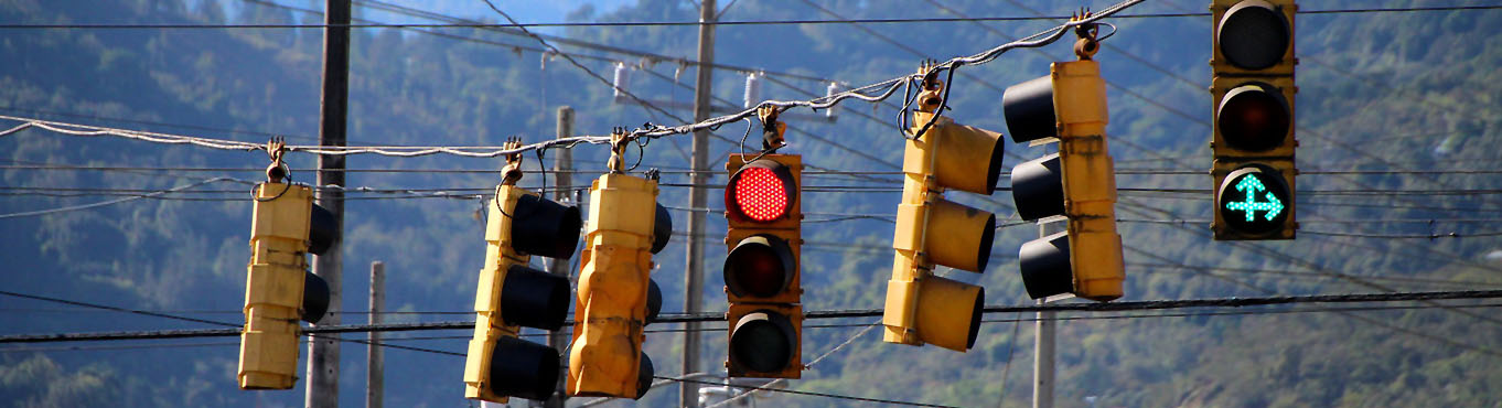 A row of traffic lights hang from a wire suspended over a small-town street