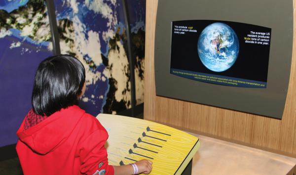 A kid learning about their carbon footprint in the Changing Earth exhibit at The Franklin Institute.