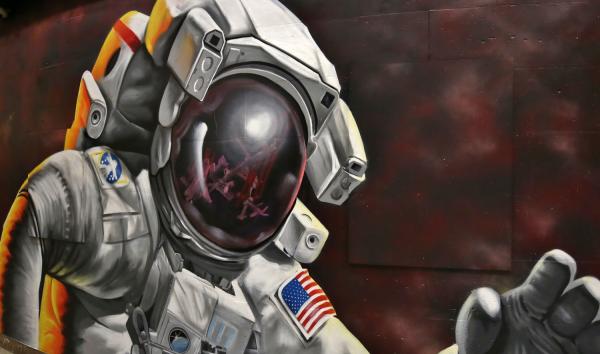 "Reflections of Greatness" mural of an Astronaut in space, with ISS reflected and Earth in the background.