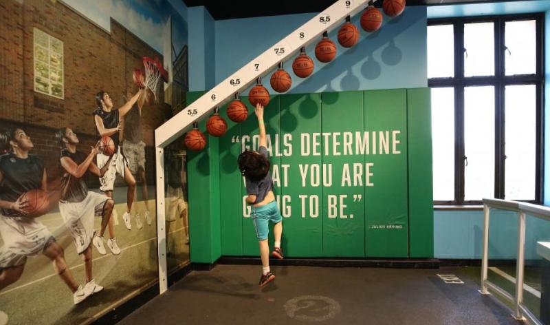 child trying to reach a high basketball
