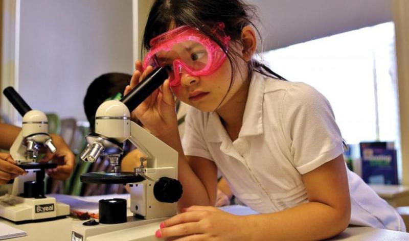 girl looking through microscope