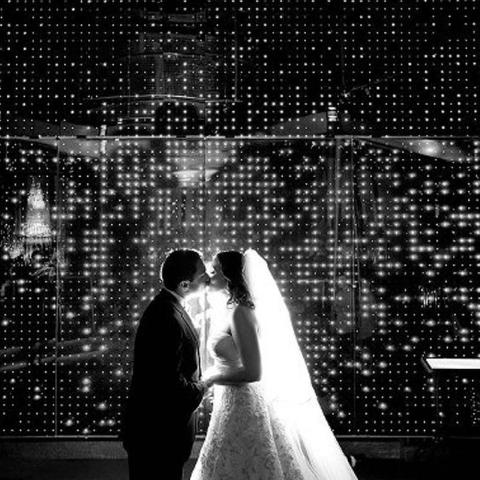 Newlyweds kissing in front of the Electricity Wall at The Franklin Institute.