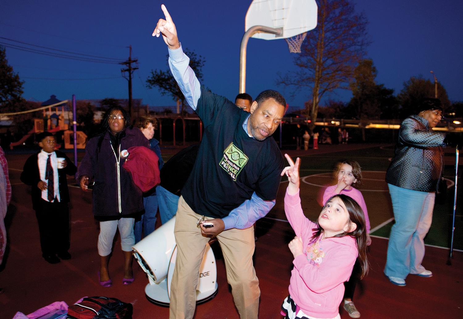 Chief Astronomer Derrick Pitts from the Franklin Insitute teaches a young girl about space.